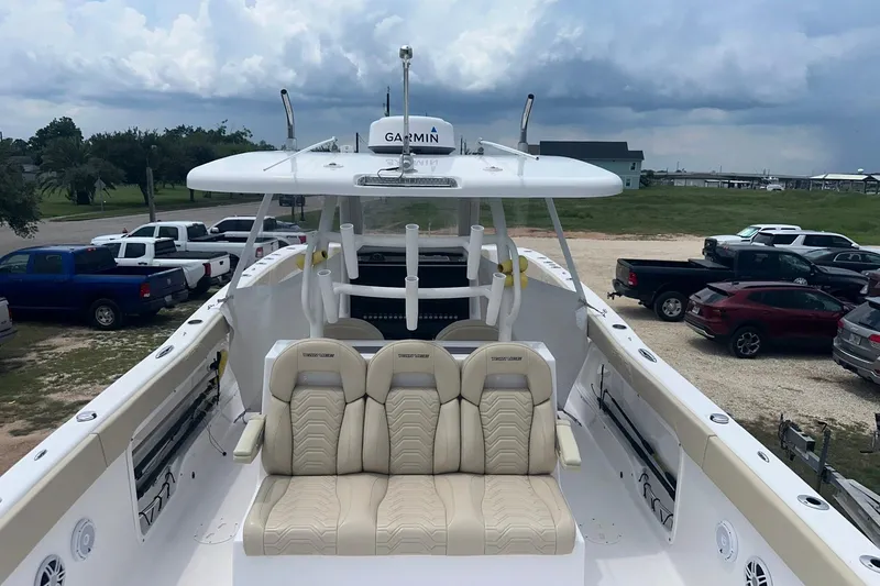 Slide: The Image of 2023 Twin Vee 340 GFX CC boat with beige seating, parked near vehicles under cloudy sky. - 32