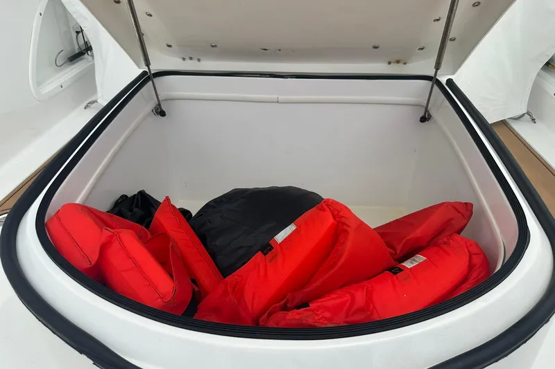 Slide: The Image of Open storage compartment with red life jackets on a 2023 Twin Vee 340 GFX CC boat. - 54
