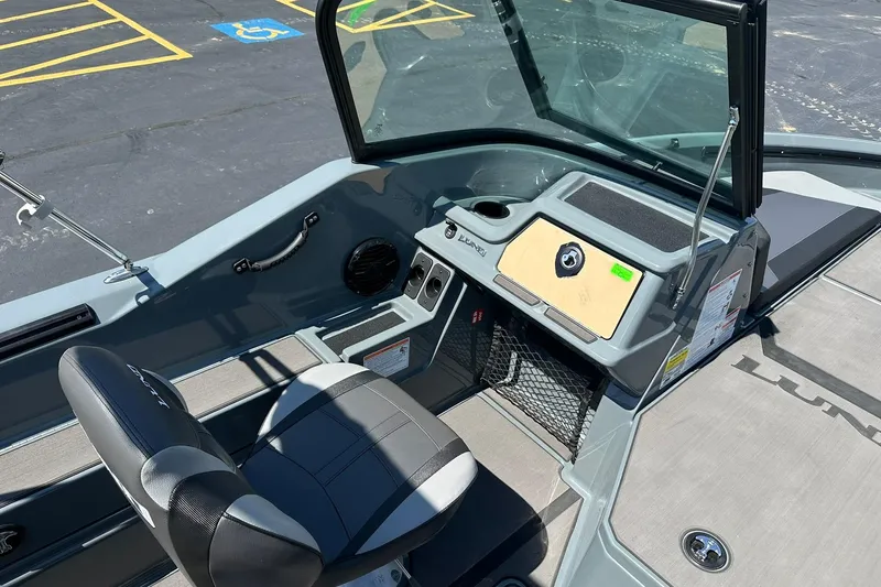 Slide: The Image of 2026 Lund 185 Impact GL boat interior with seating and dashboard in a parking lot. - 18