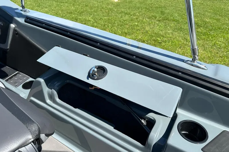 Slide: The Image of 2026 Lund 185 Impact GL boat interior with open storage compartment and cup holder. - 31