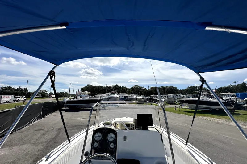 Slide: The Image of 2008 Sea Hunt Ultra 196 boat with blue canopy, parked in a marina. - 14