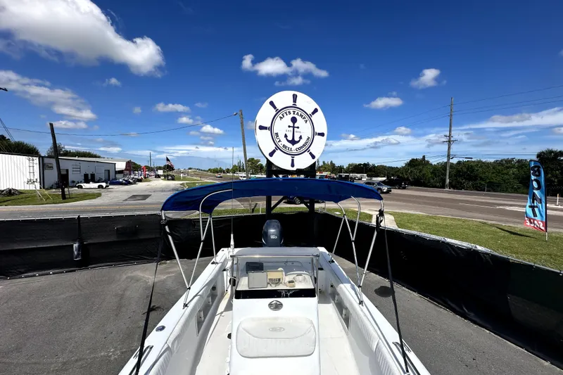 Slide: The Image of 2008 Sea Hunt Ultra 196 boat with blue canopy at a dealership under a clear sky. - 24