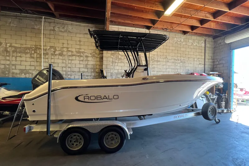 The Image of 2023 Robalo R200 Center Console boat on trailer in garage setting. - 0