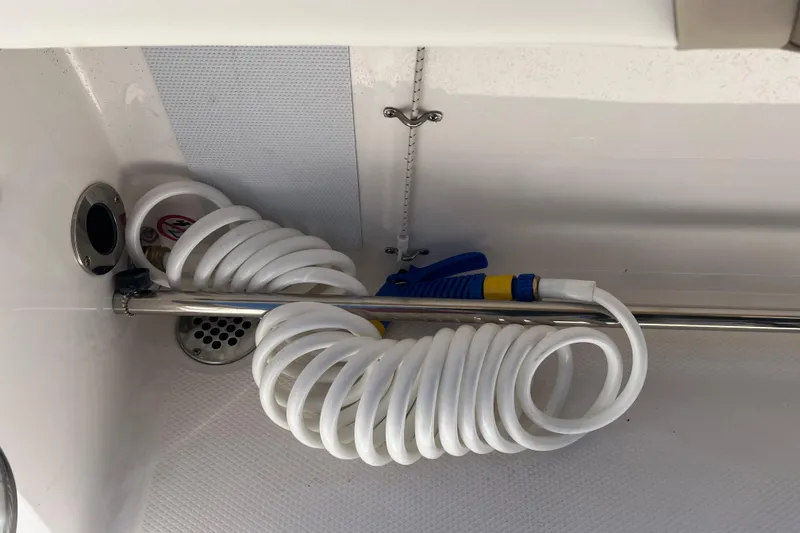 Slide: The Image of 2023 Robalo R200 Center Console boat with coiled hose and nozzle in storage compartment. - 27