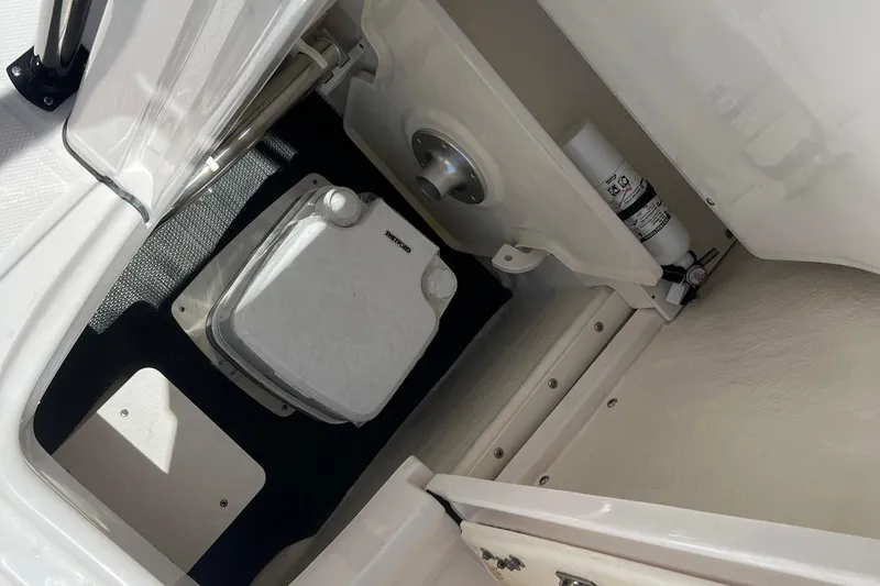 Slide: The Image of 2023 Robalo R200 Center Console boat interior with storage compartment and portable toilet. - 29
