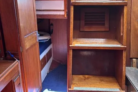 Slide: The Image of Interior of 1972 Cheoy Lee Offshore 47 Yawl, featuring wooden shelves and cozy sleeping quarters. - 11