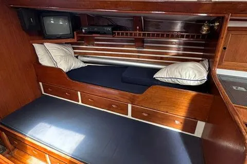 Slide: The Image of 1972 Cheoy Lee Offshore 47 Yawl cabin interior with wooden finish and cozy bedding. - 16