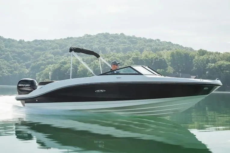 Slide: The Image of 2019 Sea Ray SPX 210 OB boat cruising on a lake with scenic forested hills. - 23