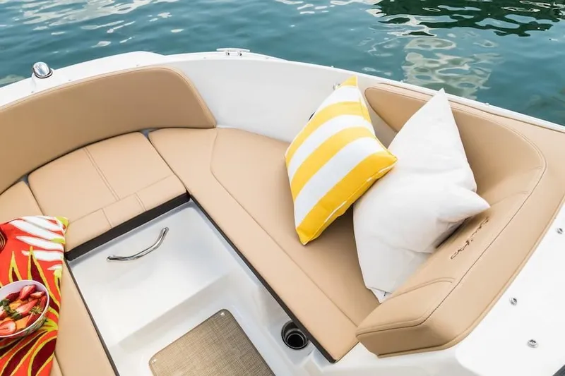 Slide: The Image of 2019 Sea Ray SPX 210 OB boat interior with tan seating, pillows, and a colorful towel. - 28