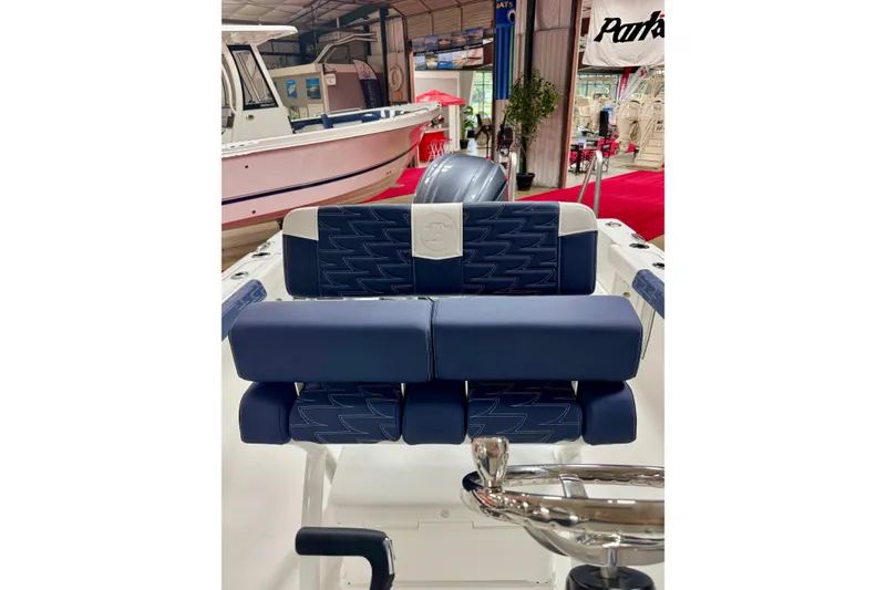 Slide: The Image of 2026 Parker 23SE Center Console boat interior with blue and white seating in showroom. - 8