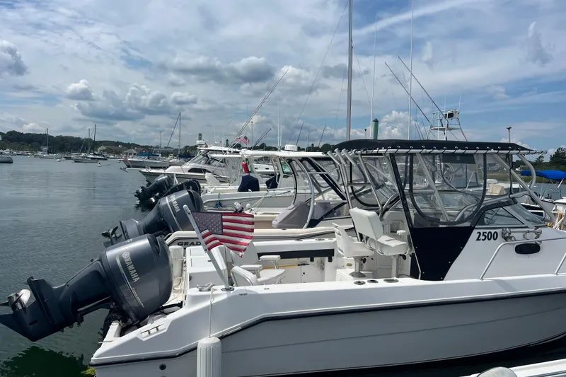 Slide: The Image of Boats docked at marina, featuring 2002 Angler 2500 WA with Yamaha engines and American flag. - 0