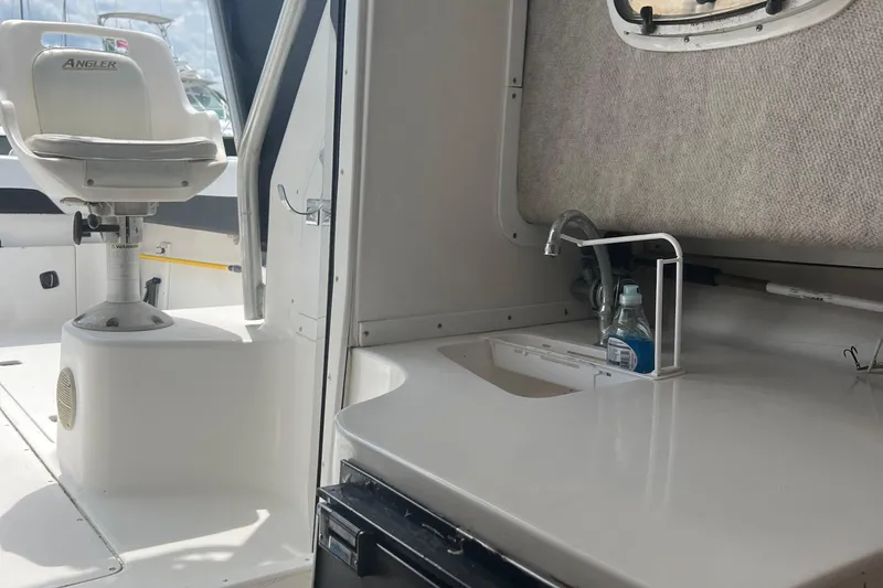 Slide: The Image of 2002 Angler 2500 WA boat interior with seating and sink area. - 12