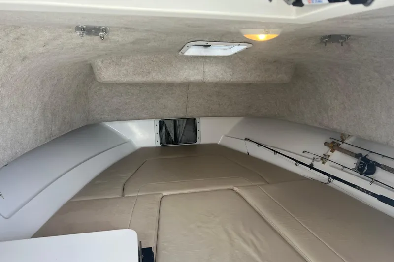 Slide: The Image of Interior cabin of 2002 Angler 2500 WA boat with fishing rods and seating. - 13