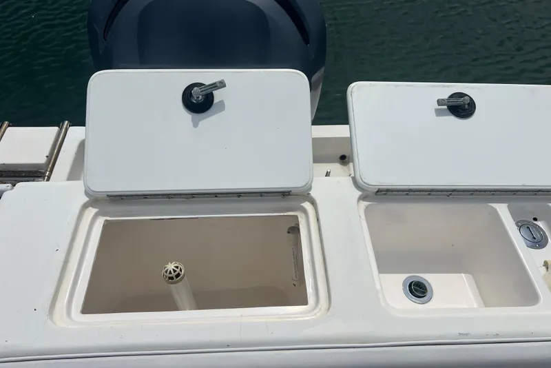 Slide: The Image of 2002 Angler 2500 WA boat storage compartments and engine, docked on water. - 15