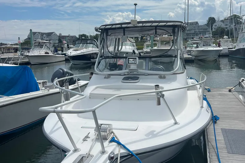 Slide: The Image of 2002 Angler 2500 WA boat docked in a marina with other vessels. - 2