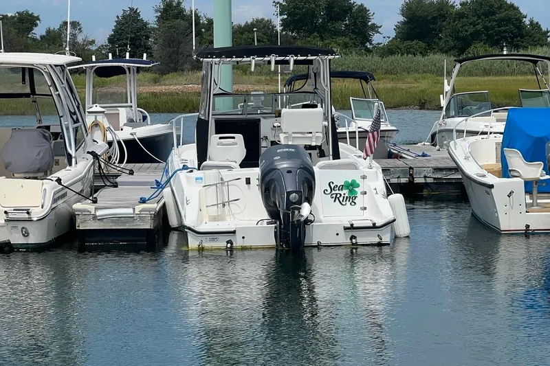 Slide: The Image of 2002 Angler 2500 WA boat docked at marina, surrounded by other vessels. - 3