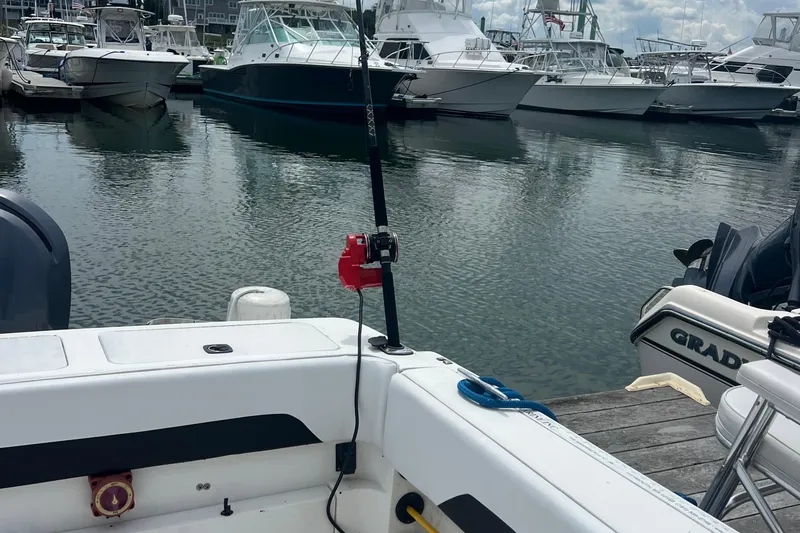 Slide: The Image of 2002 Angler 2500 WA boat docked at marina with other vessels in background. - 7