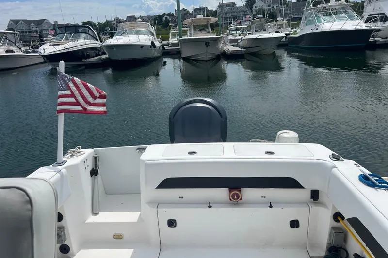 Slide: The Image of 2002 Angler 2500 WA boat docked in marina with American flag. - 8