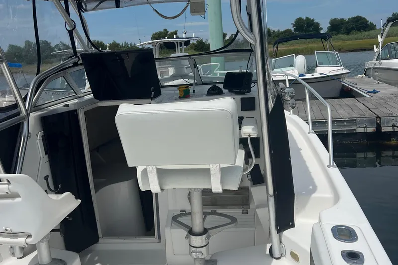 Slide: The Image of 2002 Angler 2500 WA boat interior with helm, docked at marina. - 9