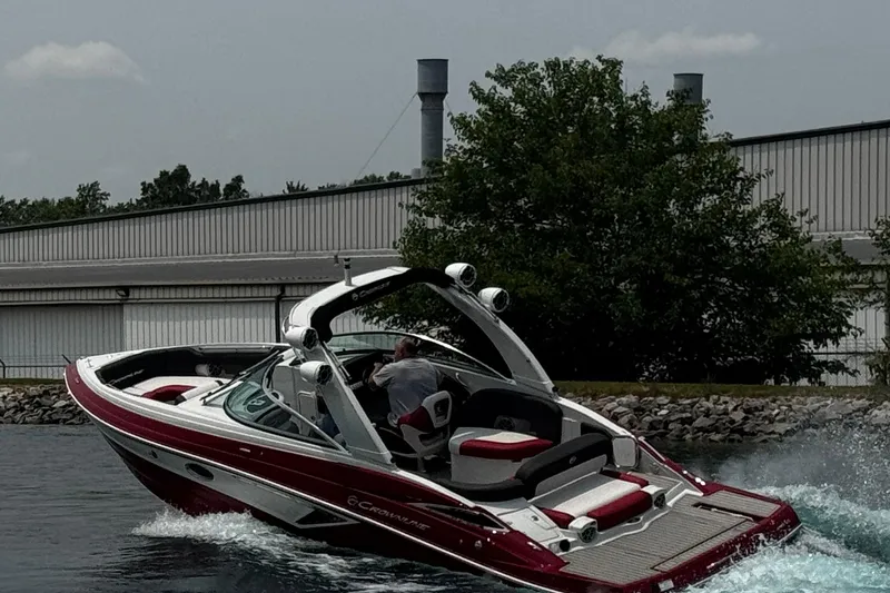 Slide: The Image of 2026 Crownline 298 SS boat cruising on a lake near industrial buildings. - 12