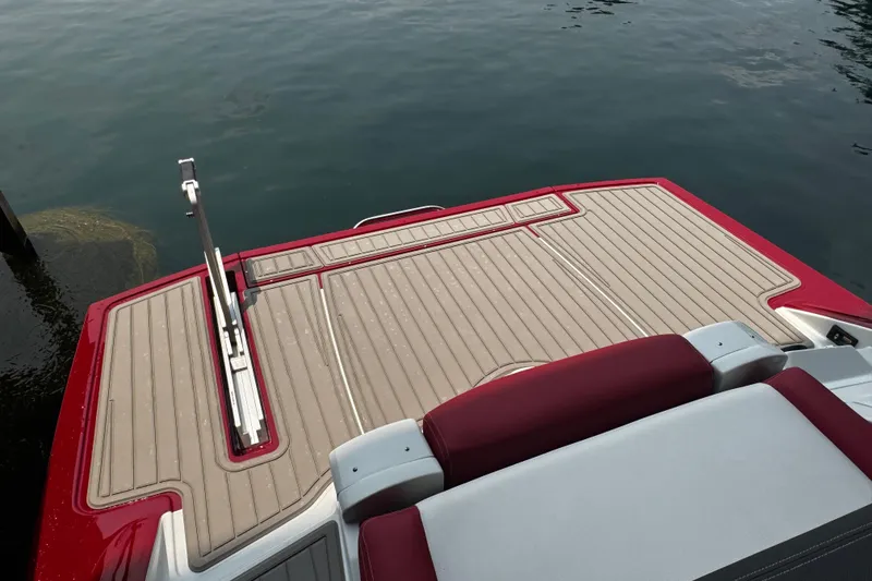 Slide: The Image of 2026 Crownline 298 SS boat swim platform with red and beige detailing on water. - 7