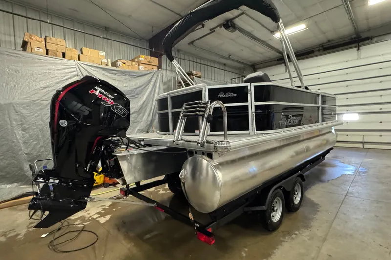 Slide: The Image of 2026 Sun Tracker Party Barge 20 DLX pontoon boat in a garage, featuring a Mercury engine. - 4
