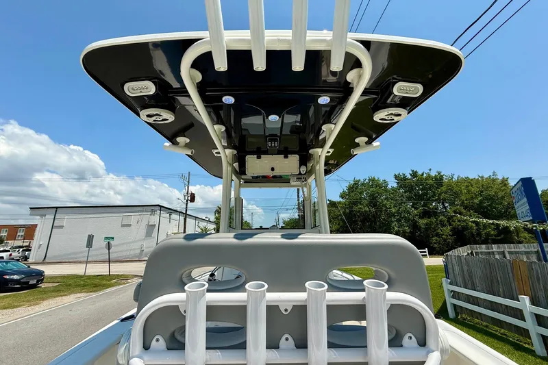 Slide: The Image of 2022 NauticStar 251 Hybrid boat with T-top and rod holders, parked outdoors. - 12