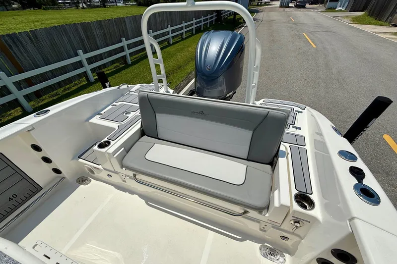 Slide: The Image of 2022 NauticStar 251 Hybrid boat interior with seating and motor, parked on a road. - 7