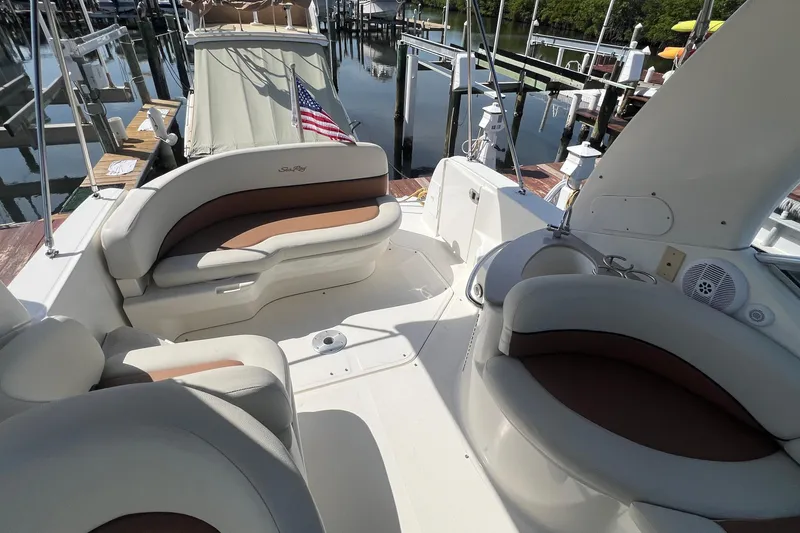 Slide: The Image of 2005 Sea Ray 260 Sundancer boat interior with seating and American flag at dock. - 13