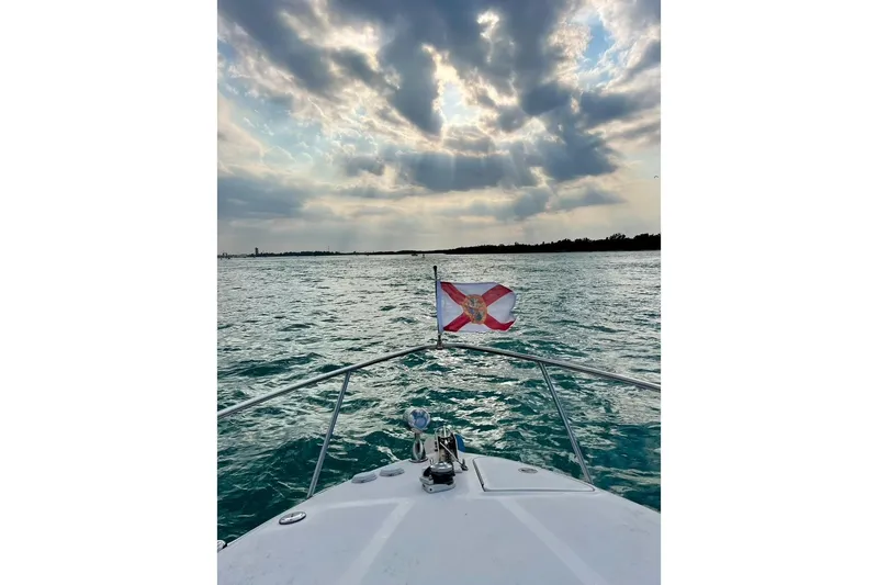 Slide: The Image of 2005 Sea Ray 260 Sundancer cruising under dramatic cloudy sky with Florida flag. - 14