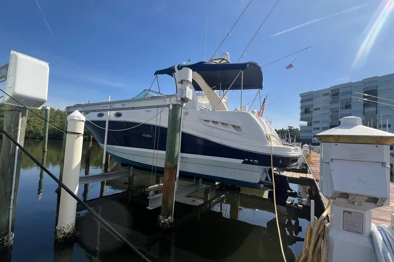 Slide: The Image of 2005 Sea Ray 260 Sundancer boat docked at marina, clear sky, modern building background. - 2