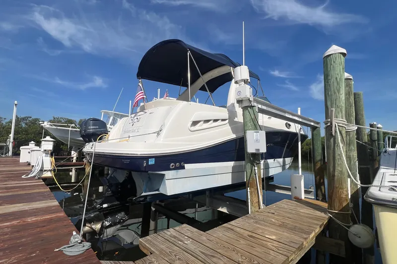Slide: The Image of 2005 Sea Ray 260 Sundancer docked, featuring a blue hull and canopy under a clear sky. - 3