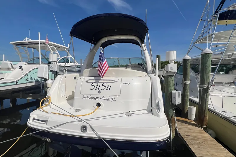 Slide: The Image of 2005 Sea Ray 260 Sundancer docked at marina, featuring American flag and "SuSu" nameplate. - 4