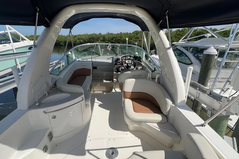 Slide: The Image of 2005 Sea Ray 260 Sundancer boat interior with seating and helm, docked at marina. - 9