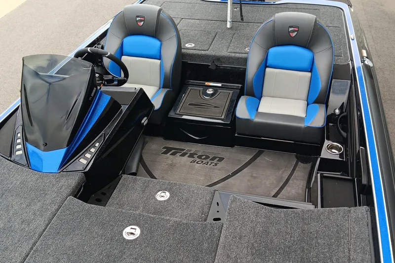 Slide: The Image of 2025 Triton 20XP boat interior with blue and gray seats, steering console, and carpeted flooring. - 13