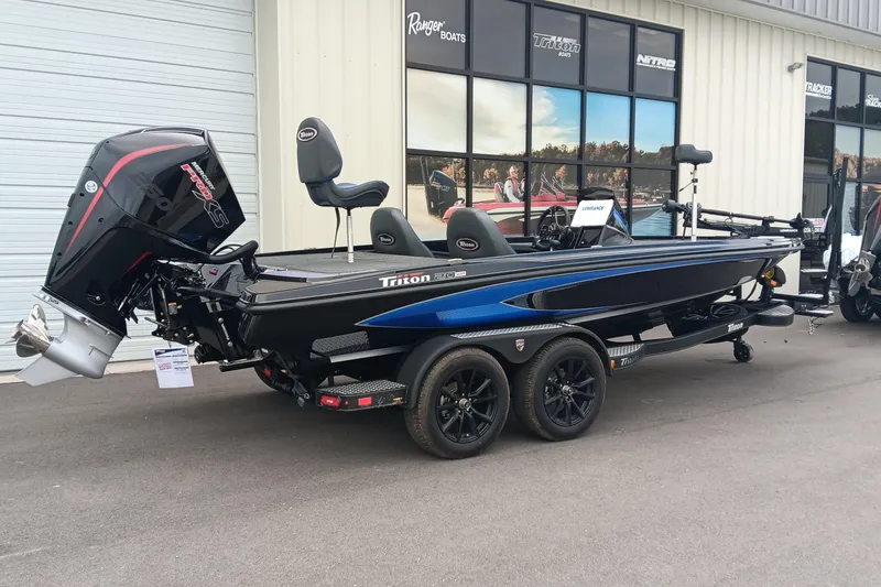 Slide: The Image of 2025 Triton 20XP boat with powerful outboard motor, parked outside a showroom. - 2