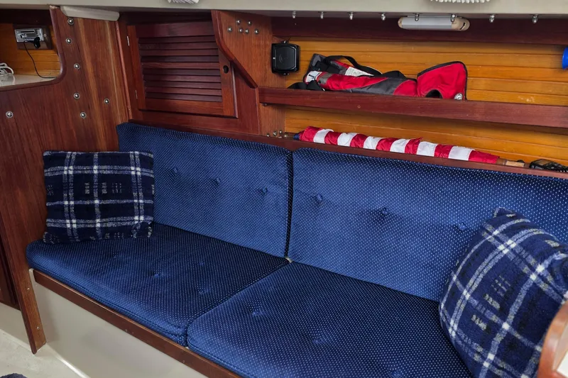 Slide: The Image of Interior of 1987 Catalina 30 MkII sailboat with blue cushioned seating and plaid pillows. - 11