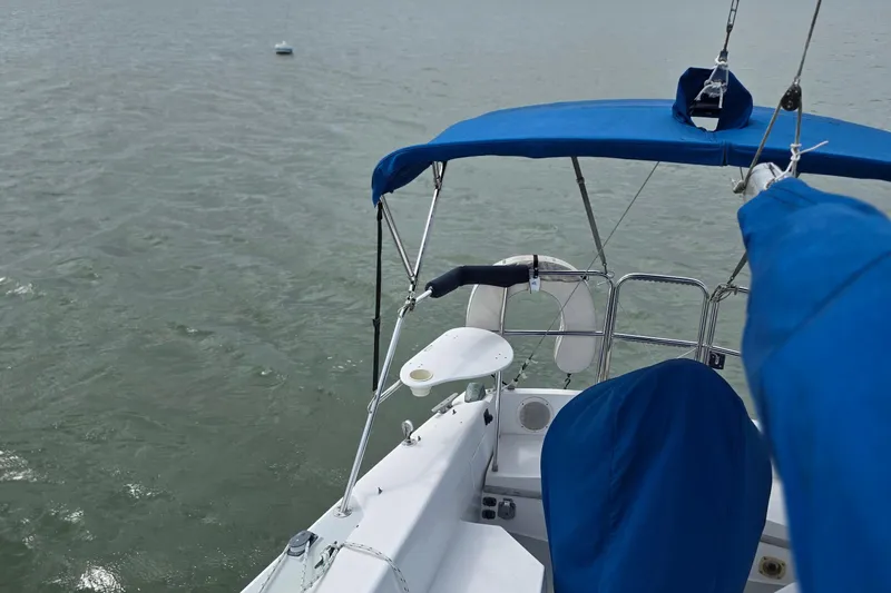 Slide: The Image of 1987 Catalina 30 MkII sailboat with blue canopy on calm water. - 3