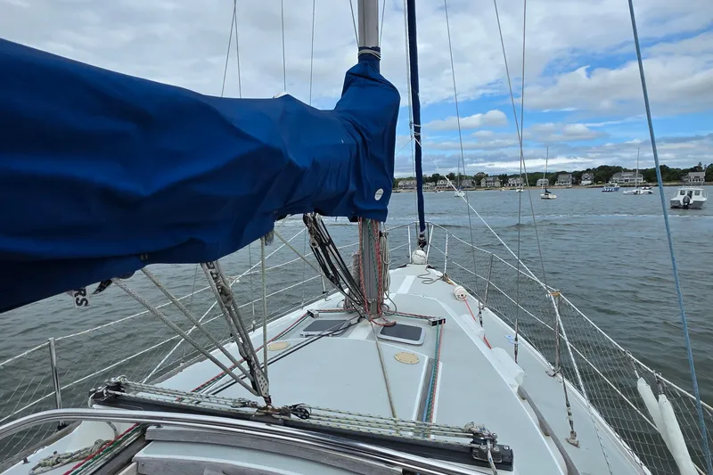 Slide: The Image of 1987 Catalina 30 MkII sailboat deck with blue sail cover, moored in a scenic harbor. - 8