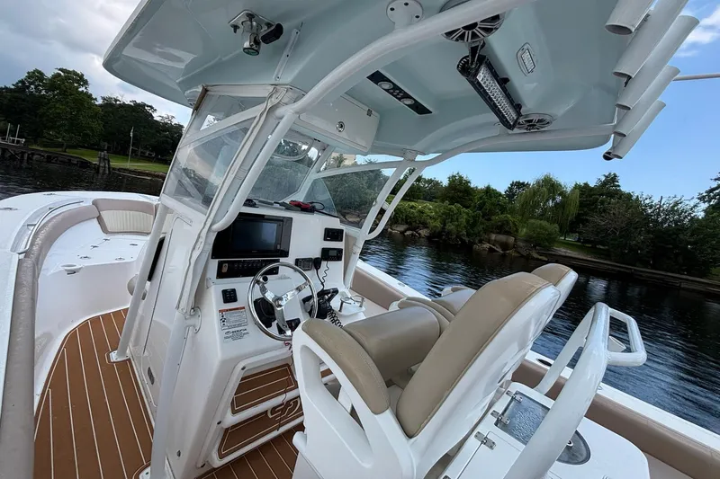 Slide: The Image of 2016 Sea Fox 286 boat interior with helm, steering wheel, and seating on a calm waterway. - 10