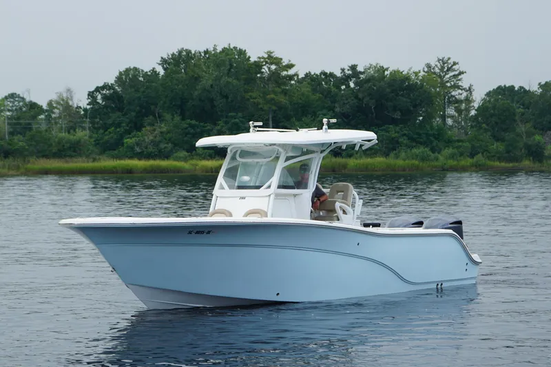 Slide: The Image of 2016 Sea Fox 286 boat on calm water with lush green shoreline background. - 2
