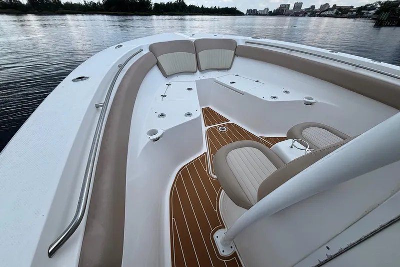 Slide: The Image of 2016 Sea Fox 286 boat interior with cushioned seating and wood-style flooring on calm water. - 24