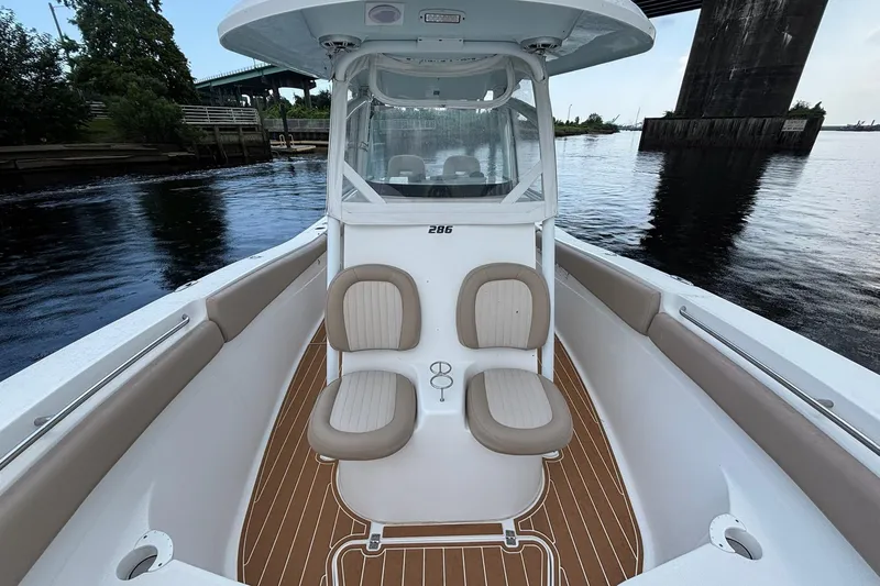 Slide: The Image of 2016 Sea Fox 286 boat interior with dual seats and wooden deck, docked by a bridge. - 8