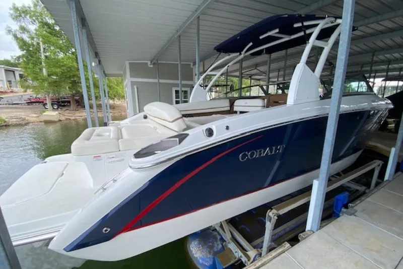 Slide: The Image of 2015 Cobalt R7 boat docked under a covered marina, featuring sleek design and spacious seating. - 2