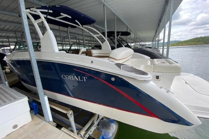 Slide: The Image of 2015 Cobalt R7 boat docked under a covered marina, featuring sleek blue and white design. - 3
