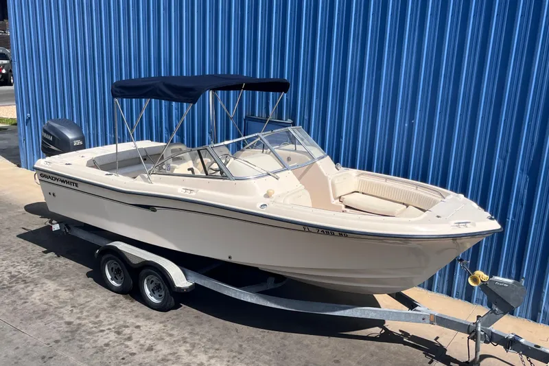 Slide: The Image of 2006 Grady-White Tournament 225 boat on trailer, parked by blue wall. - 2