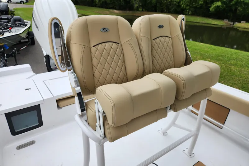 Slide: The Image of 2026 Sportsman Masters 247 Bay Boat with tan cushioned seats, docked near a lake. - 24