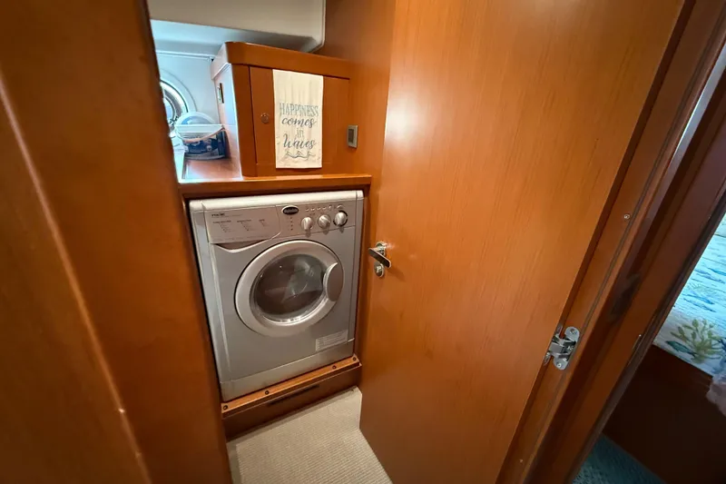 Slide: The Image of Laundry area inside 2018 Beneteau Swift Trawler 44, featuring a compact washing machine. - 25