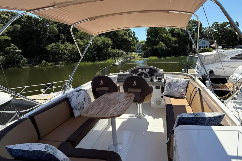 Slide: The Image of 2018 Beneteau Swift Trawler 44 with spacious outdoor seating and helm, docked by a serene river. - 28