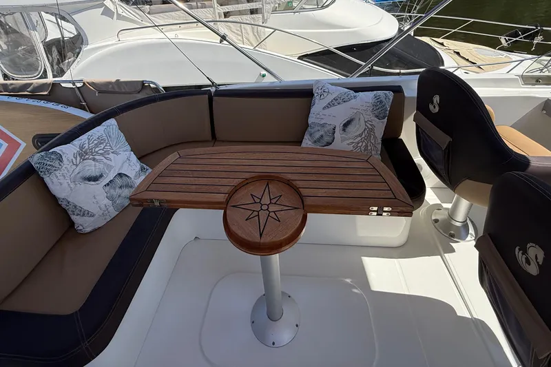 Slide: The Image of 2018 Beneteau Swift Trawler 44 cockpit with wooden table and cushioned seating. - 29